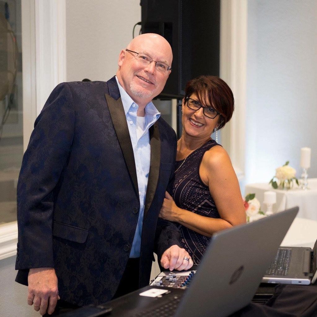 A man and woman posing for a picture in front of an open laptop.