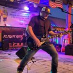 Guitarist performing on outdoor stage at night.